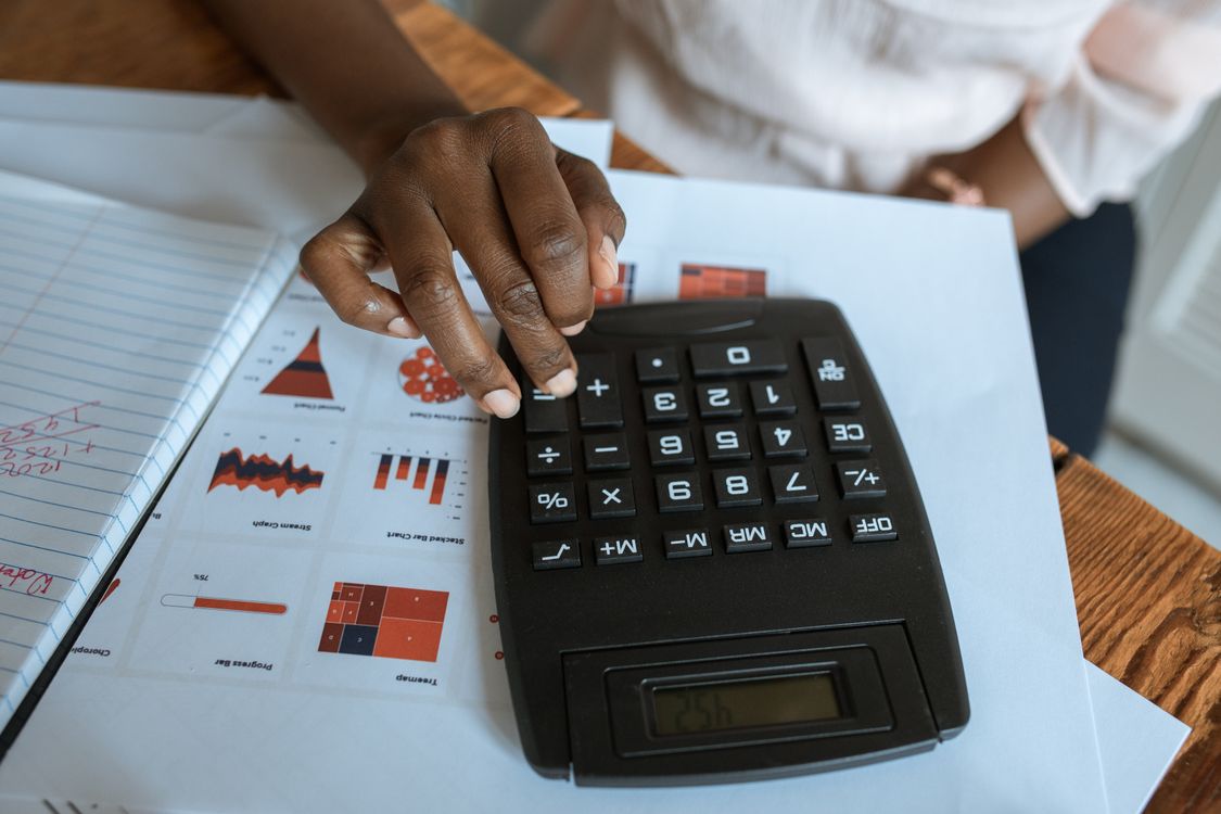 Mãos a utilizar uma calculadora sobre gráficos financeiros